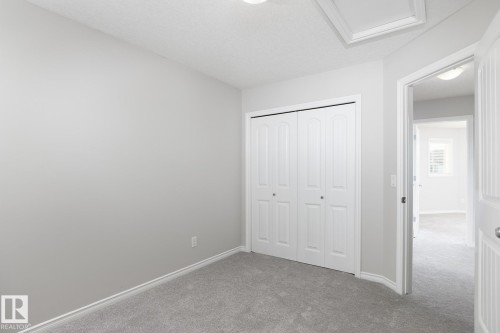Neutral gray wall tones, plush gray carpeting, white bi-fold closet doors, and recessed ceiling lighting - 441 Songhurst Place, Leduc, AB 