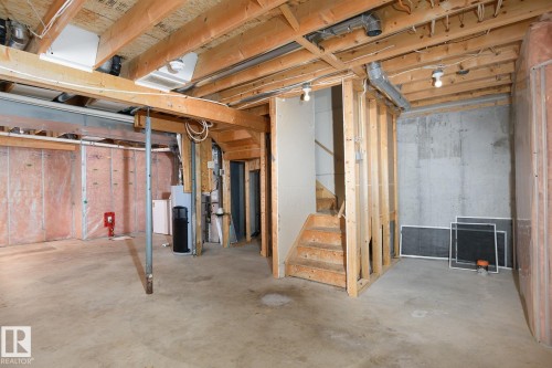 Unfinished basement featuring exposed wood joists, concrete flooring, and roughed-in framing - 441 Songhurst Place, Leduc, AB 