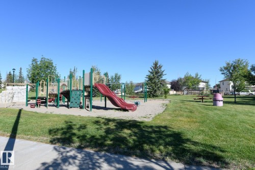 Park with a playground structure, sandbox area, and green lawn - 441 Songhurst Place, Leduc, AB 