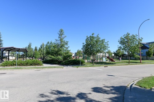 Community green space with a playground, mature trees, and a covered seating area - 441 Songhurst Place, Leduc, AB 