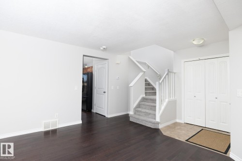 Wood-finish flooring, carpeted staircase with white railings, and white bi-fold closet doors - 441 Songhurst Place, Leduc, AB 