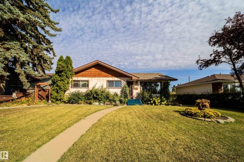Front exterior featuring a gabled roof, light-colored siding, front lawn with a curved pathway, and established landscaping - 4808 106 Avenue Nw, Edmonton, AB 