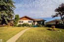 Front exterior featuring a gabled roof, light-colored siding, front lawn with a curved pathway, and established landscaping - 4808 106 Avenue Nw, Edmonton, AB 