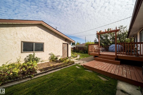Expansive backyard featuring a multi-level wood deck with a pergola, a manicured lawn, and a separate structure with stucco siding - 4808 106 Avenue Nw, Edmonton, AB 