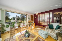Expansive picture window, light wood-finish flooring, decorative wall mirrors, ceiling-mounted light fixtures, and a wood entry door - 