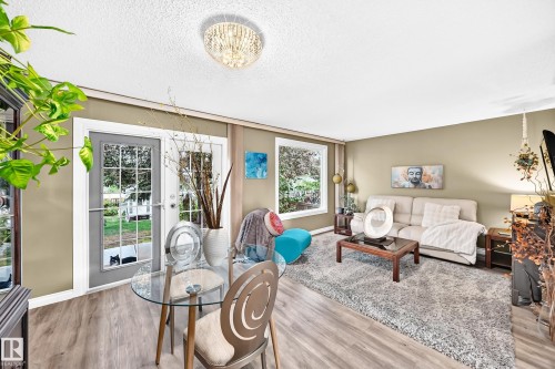 Light-toned walls with wood-finish flooring, featuring a crystal-adorned ceiling light and transom windows - 5620 93A Avenue Nw, Edmonton, AB 