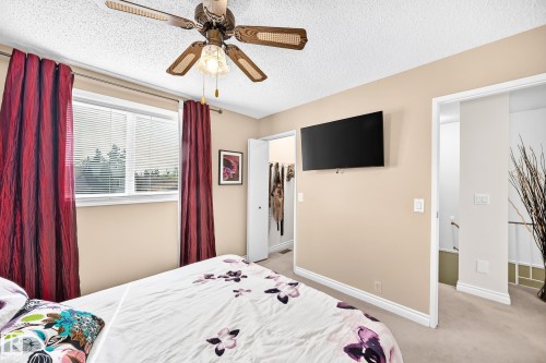 Recessed window with horizontal blinds, overhead ceiling fan with light fixture, wall-mounted television, and neutral wall paint - 5620 93A Avenue Nw, Edmonton, AB 