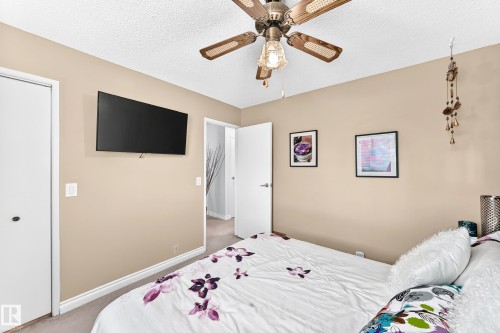 Ceiling fan with light fixture, wall-mounted television, neutral wall color, white trim, and white doors - 5620 93A Avenue Nw, Edmonton, AB 