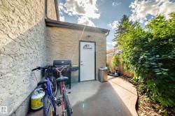 Concrete patio area featuring a white exterior door with an arched window, stucco exterior wall, and a wood fence - 