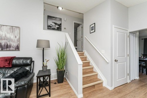 Staircase with wood-finish treads and white risers, framed by light gray walls and wood-finish flooring - 6 Kiniski Crescent Nw, Edmonton, AB 