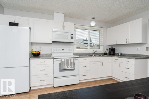 White cabinetry with brushed nickel hardware, grey countertops, white appliances, and wood-finish flooring - 6 Kiniski Crescent Nw, Edmonton, AB 