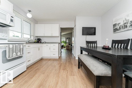 Kitchen featuring wood-finish flooring, white cabinetry, a built-in oven, and a built-in microwave - 6 Kiniski Crescent Nw, Edmonton, AB 