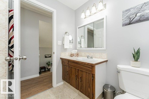 Bathroom vanity with wood-finish cabinetry, a white basin, and a mirrored medicine cabinet - 6 Kiniski Crescent Nw, Edmonton, AB 