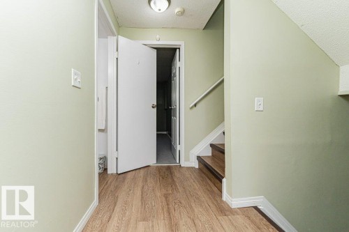 Wood-finish flooring, staircase with wood treads, white handrail, recessed ceiling light fixture, and interior door with hardware - 6 Kiniski Crescent Nw, Edmonton, AB 