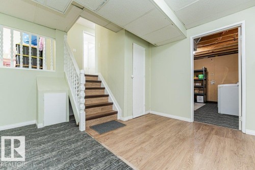 Wood-finish flooring, staircase with wood treads, white painted balusters, and a built-in storage door - 6 Kiniski Crescent Nw, Edmonton, AB 