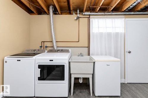 Laundry area featuring a utility sink, light wood-finish flooring, and exposed ceiling beams - 6 Kiniski Crescent Nw, Edmonton, AB 