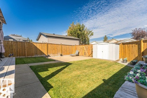 Expansive backyard featuring a manicured lawn, concrete patio, and privacy fencing - 6 Kiniski Crescent Nw, Edmonton, AB 