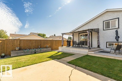 Exterior featuring a rear deck with a pergola, sliding glass door access, an adjacent concrete patio, a wooden privacy fence, and a raised garden bed - 6 Kiniski Crescent Nw, Edmonton, AB 