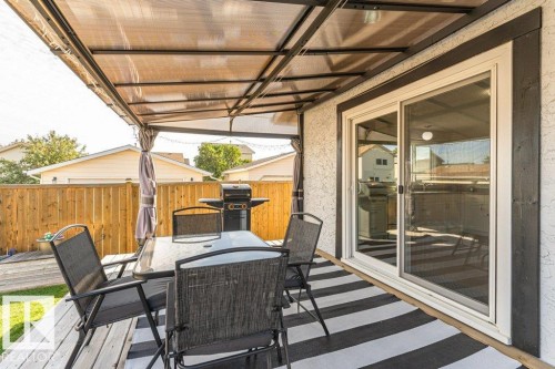 Outdoor patio with a translucent covered pergola, wood-finish decking, and sliding glass door access - 6 Kiniski Crescent Nw, Edmonton, AB 