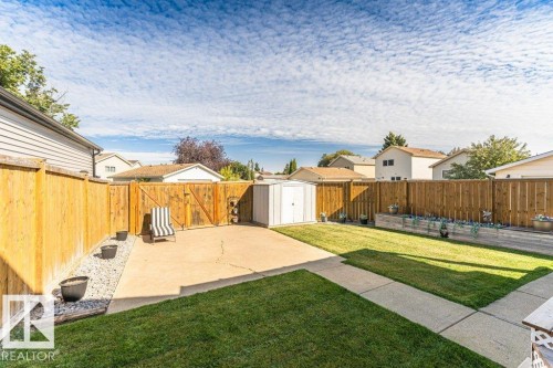 Expansive backyard featuring a manicured lawn, concrete patio, perimeter wood fencing, and a storage shed - 6 Kiniski Crescent Nw, Edmonton, AB 