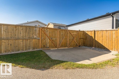 Wood privacy fence with double gate entry, concrete pad, and gravel accent - 6 Kiniski Crescent Nw, Edmonton, AB 
