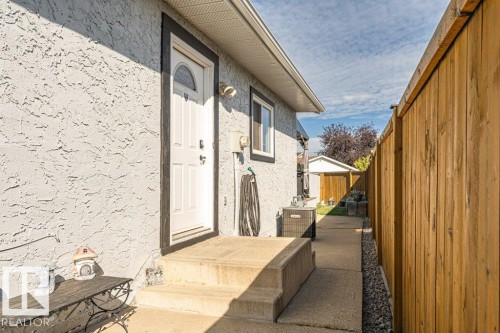 Stucco exterior with a white entry door, concrete steps, and a privacy fence - 6 Kiniski Crescent Nw, Edmonton, AB 