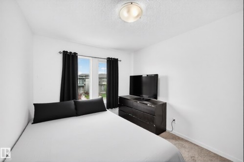 Room featuring a flush-mount ceiling light, white walls, and a window with black curtains - 19716 27 Avenue Nw, Edmonton, AB - Indoor Photo Showing Bedroom