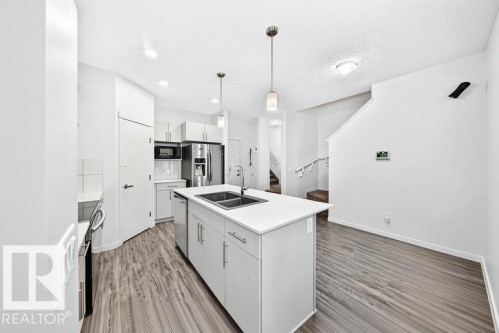 Contemporary kitchen with a central island featuring a double-basin sink and pendant lighting - 19716 27 Avenue Nw, Edmonton, AB - Indoor Photo Showing Kitchen With Double Sink With Upgraded Kitchen