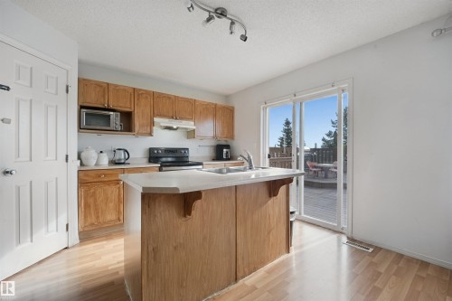 Kitchen with wood-finish cabinetry, built-in microwave, and a center island - 15911 38 Street Nw, Edmonton, AB 