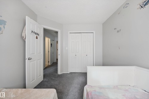Bedroom featuring carpet flooring, white paneled doors, and bi-fold closet doors - 15911 38 Street Nw, Edmonton, AB 