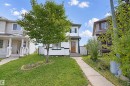 White siding exterior with a wood-finish front door, concrete walkway, and a mature tree in the front yard - 15911 38 Street Nw, Edmonton, AB 