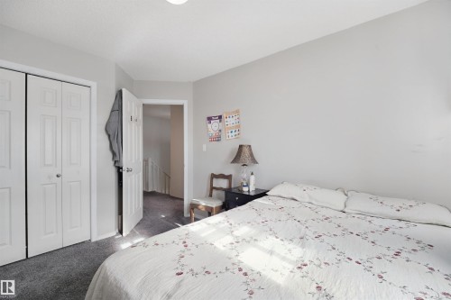 Light gray wall paint, textured ceiling, gray carpet flooring, white bi-fold closet doors, and a white interior door - 15911 38 Street Nw, Edmonton, AB 
