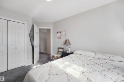Light gray wall paint, textured ceiling, gray carpet flooring, white bi-fold closet doors, and a white interior door - 