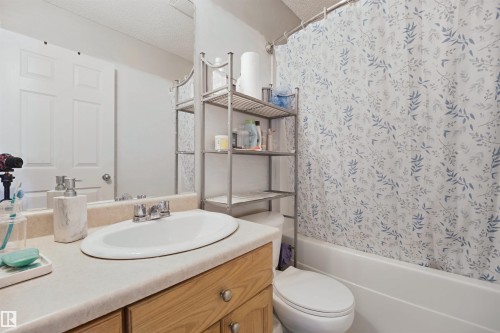 Vanity with an integrated white sink, wood-finish cabinetry, and a light-colored countertop - 15911 38 Street Nw, Edmonton, AB 
