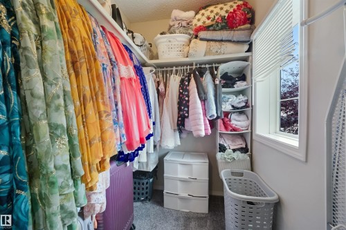 Walk-in closet featuring extensive hanging storage, multiple shelving units, and a window for natural light - 15911 38 Street Nw, Edmonton, AB 