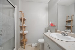 Frosted glass shower enclosure, single vanity with integrated sink, chrome faucet, wall-mounted mirror, and neutral wall paint - 