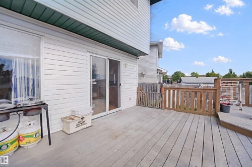Expansive outdoor deck with wood railing, featuring a sliding glass door and an exterior window - 15911 38 Street Nw, Edmonton, AB 