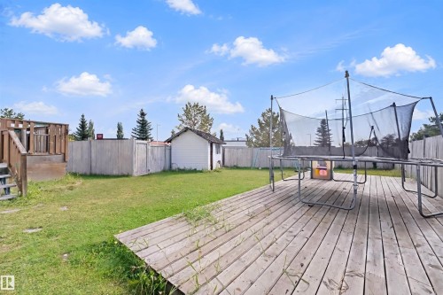 Expansive backyard with a wooden deck, separate elevated wooden deck structure, fenced perimeter, and a detached shed - 15911 38 Street Nw, Edmonton, AB 