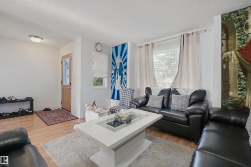 Wood-finish flooring throughout, framed window with roller blind, recessed lighting, and a light wood-tone entry door with decorative glass inserts - 15911 38 Street Nw, Edmonton, AB 