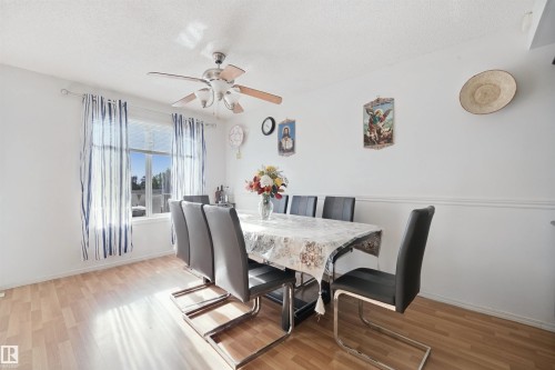 Wood-finish flooring, ceiling fan with light fixture, window with drapes, and chair rail molding - 15911 38 Street Nw, Edmonton, AB 