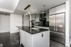 Kitchen featuring an island with a black countertop, stainless steel appliances, dark wood-finish flooring, and white cabinetry - 