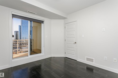 Sliding glass door leading to a balcony, wood-finish flooring, white walls, and a modern five-panel interior door - #1902 10388 105 St Nw, Edmonton, AB 