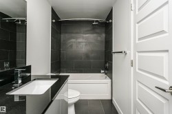 Bathroom featuring a deep soaking tub with subway tile surround, a sleek vanity with an integrated sink, a contemporary chrome faucet, and a panel-style interior door - 