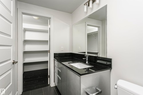 Modern vanity with a rectangular undermount sink, dark stone countertop, and contemporary faucet - #1902 10388 105 St Nw, Edmonton, AB 