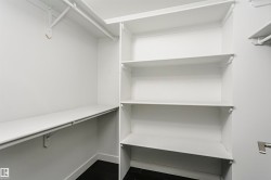 Built-in shelving, multiple hanging rods, and dark wood-finish flooring - 