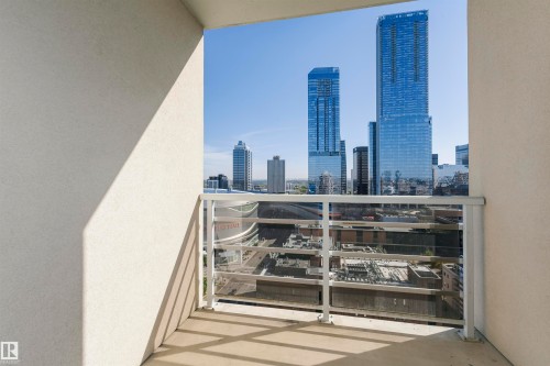 Private balcony with a concrete floor, glass and metal railing, and city skyline backdrop - #1902 10388 105 St Nw, Edmonton, AB 