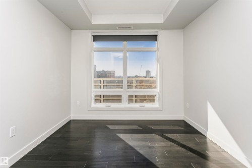 Recessed ceiling, large window with roller shade, dark wood-finish flooring, white walls, and white trim - #1902 10388 105 St Nw, Edmonton, AB 