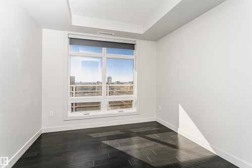 Large window offering city scenery, recessed ceiling detail, dark wood-finish flooring, and light-toned walls - #1902 10388 105 St Nw, Edmonton, AB 