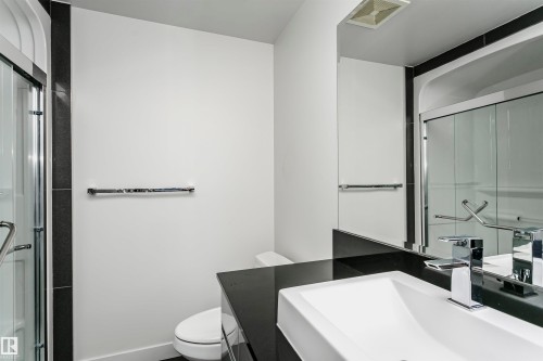Contemporary bathroom featuring a dark countertop, integrated rectangular basin, and chrome faucet - #1902 10388 105 St Nw, Edmonton, AB 