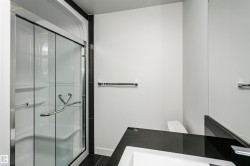 Glass-enclosed shower with integrated seating, chrome fixtures, and a sleek black countertop - 